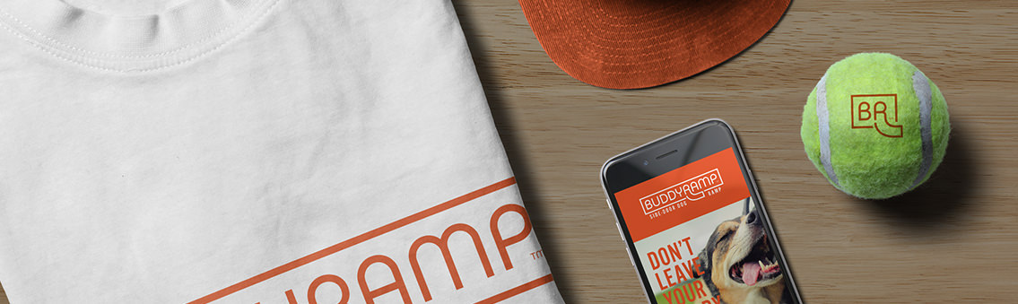 A smartphone, white t-shirt, grey cap and tennis ball displaying the Buddy Ramp logo.