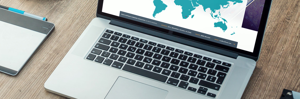 Laptop showcasing Huffman Corridor Consulting website on a wooden table.