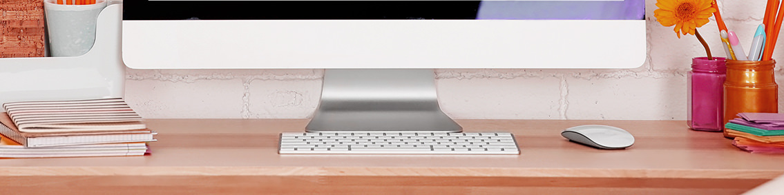 A desk, keyboard, bottom of a monitor and office paraphernalia.