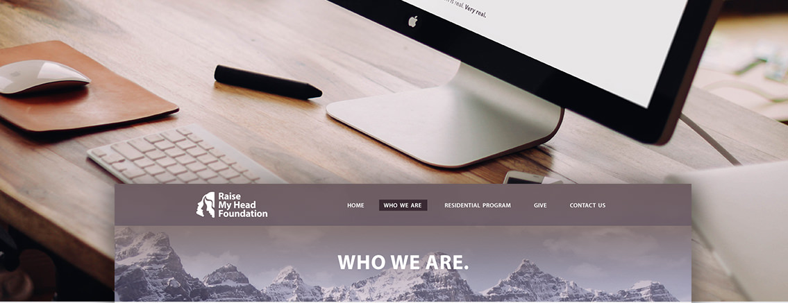 Bottom half of a monitor and the home page and navigation bar of the “Raise My Head Foundation” website.