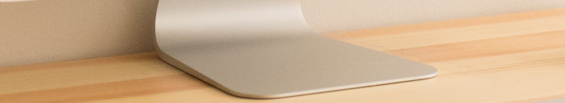 A Mac stand resting on a wooden desk.