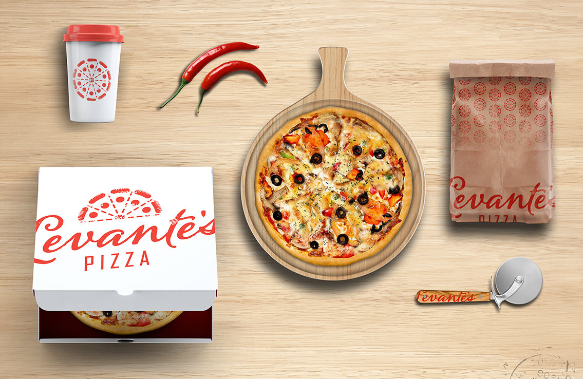 Veggie pizza on tray surrounded by Levante's Pizza box, bag, coffee cup, pizza slicer, and peppers.