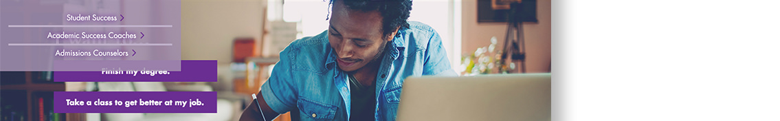 Man in blue shirt smiling in front of open computer.